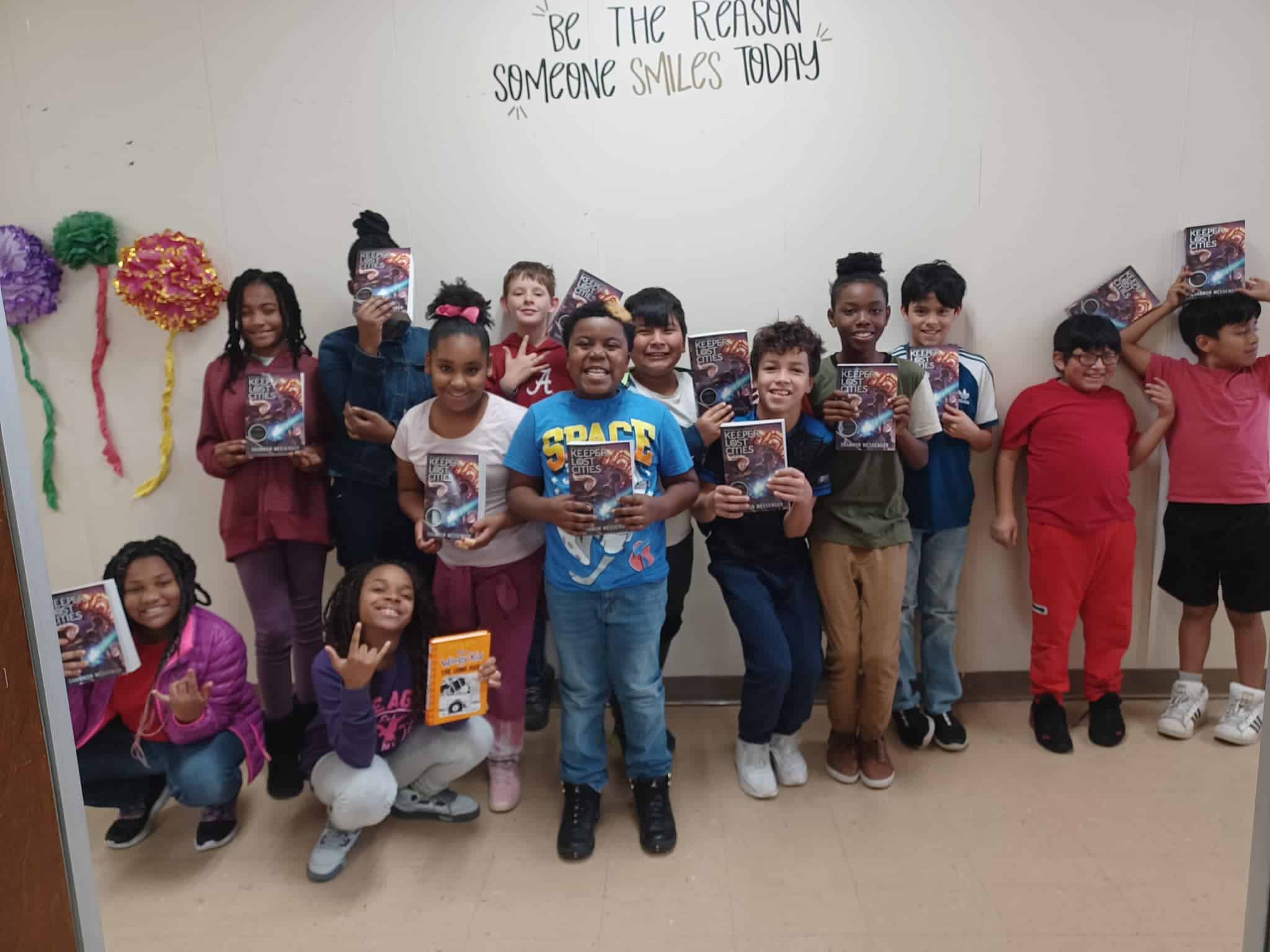 students hold books and smile